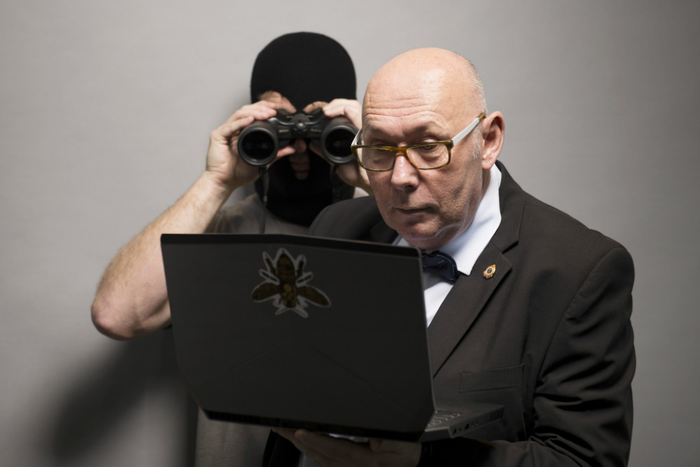 Guy with binoculars behind someone working on a computerThe Feeling you are being watched