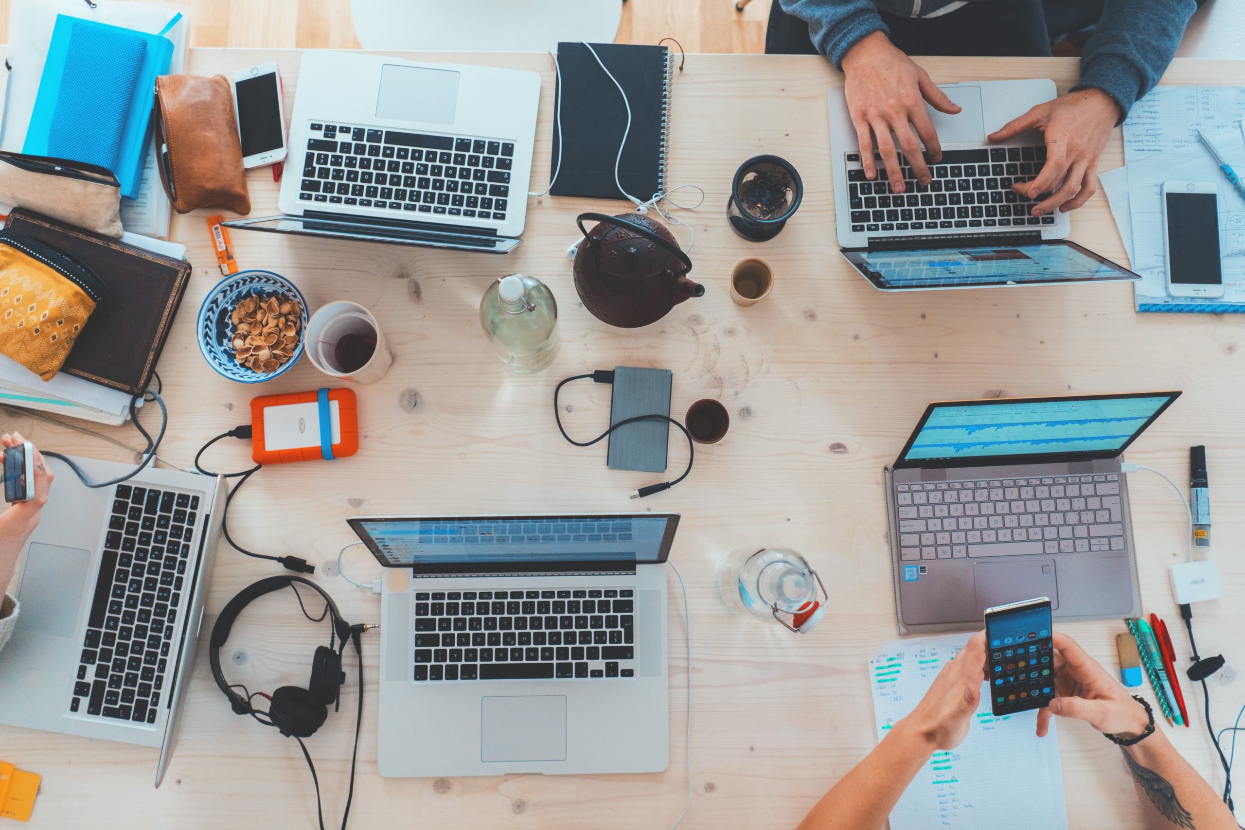 desk with several laptops and hands