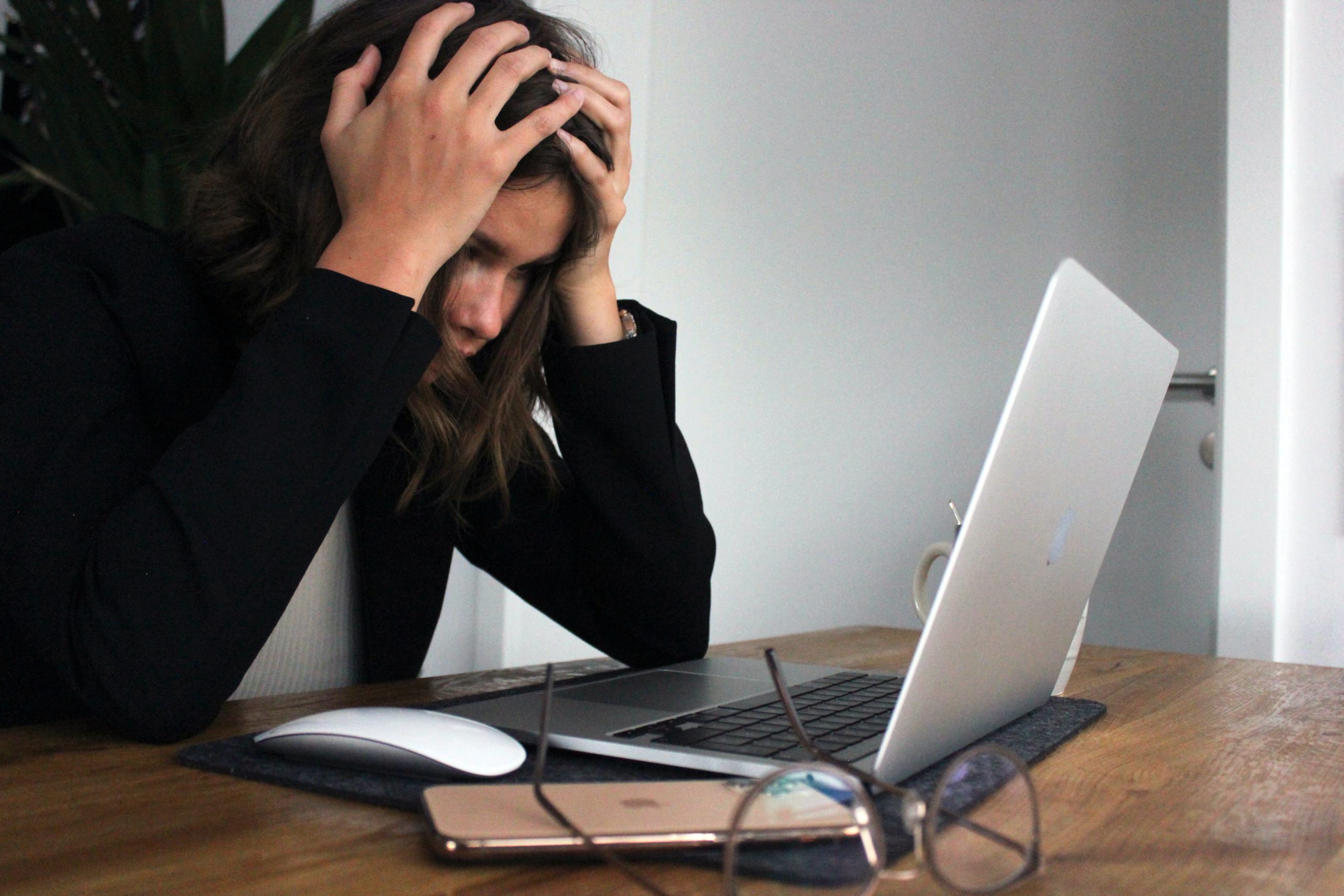 Woman looking at her laptop with hands on her head in frustration